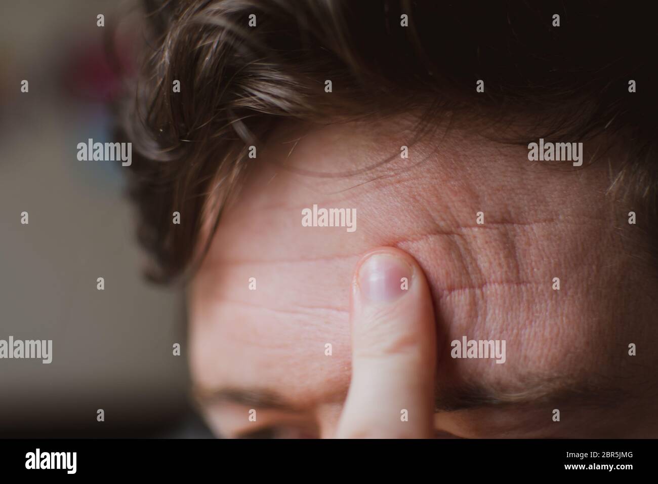 A close up shot of a man rubbing his forehead with one finger. Stock Photo