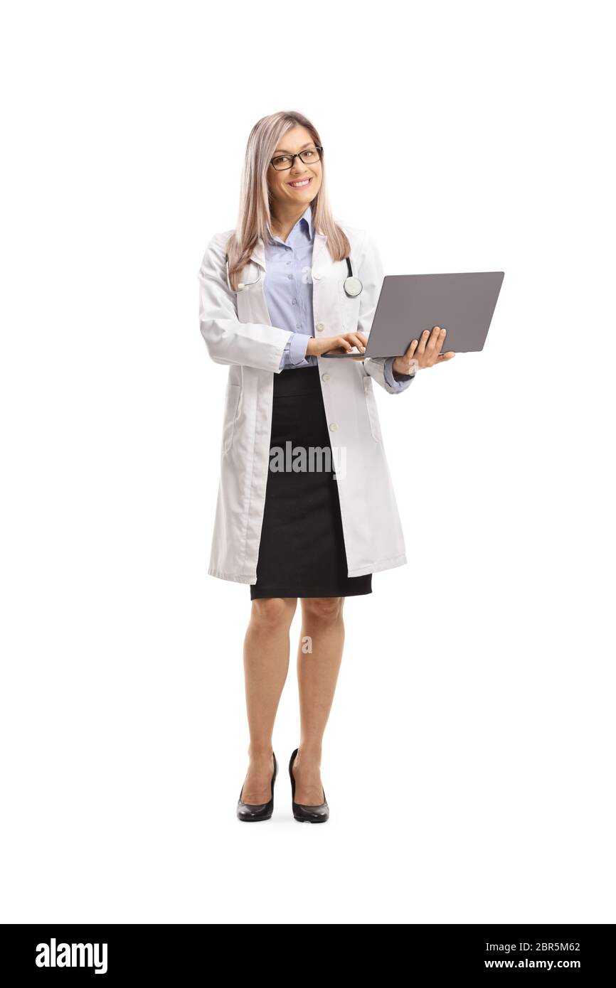 Full length portrait of a female doctor standing and holding a laptop computer isolated on white background Stock Photo