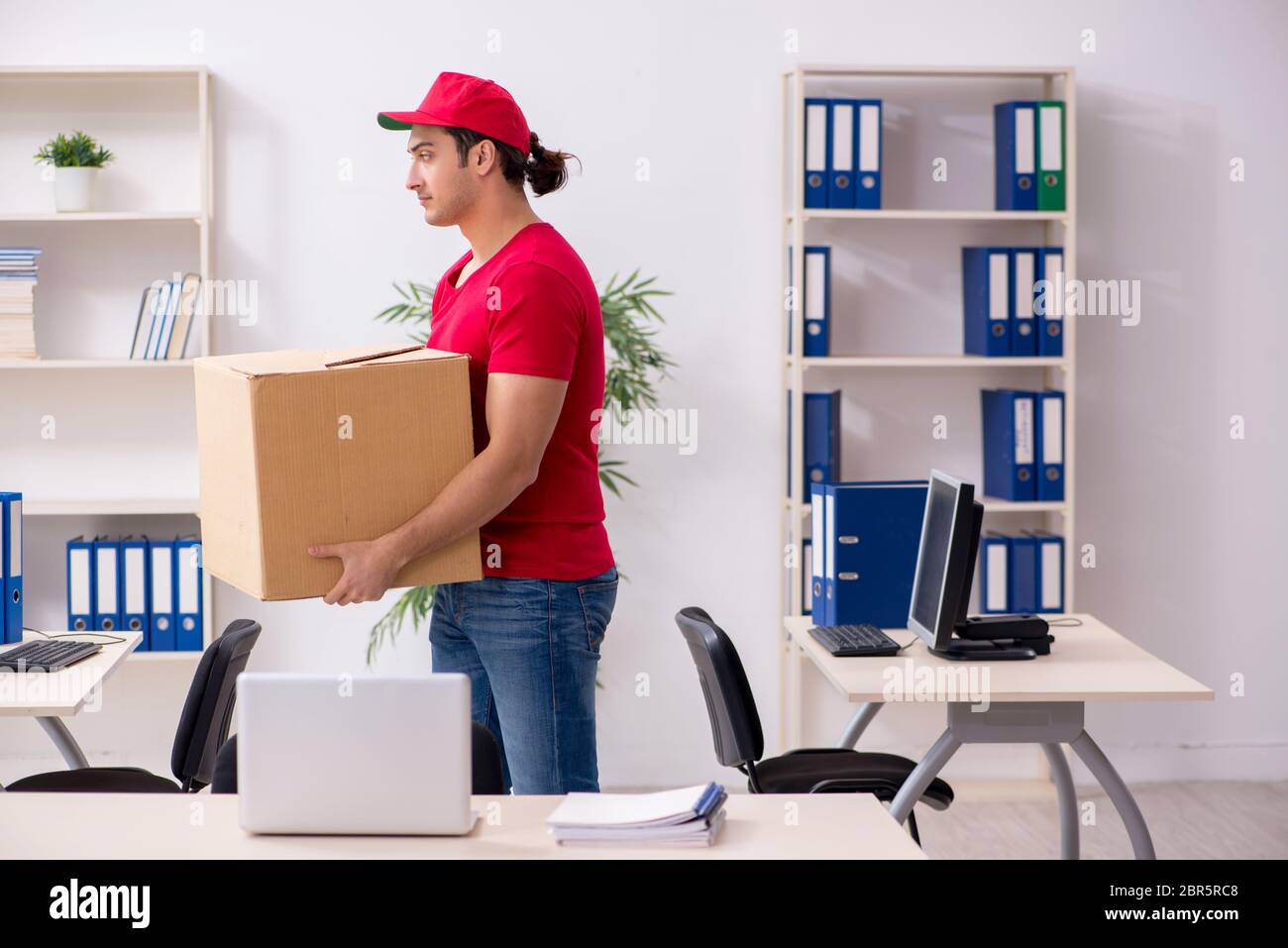 Young courier delivering postbox to the office Stock Photo Alamy