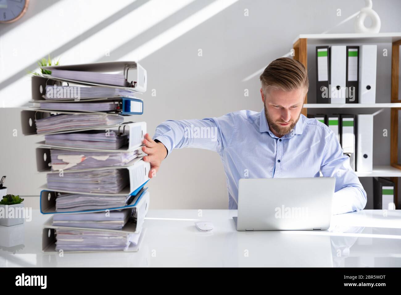Businessperson Pushing Paper Documents Away And Working With Digital Documents On Computer Instead Stock Photo