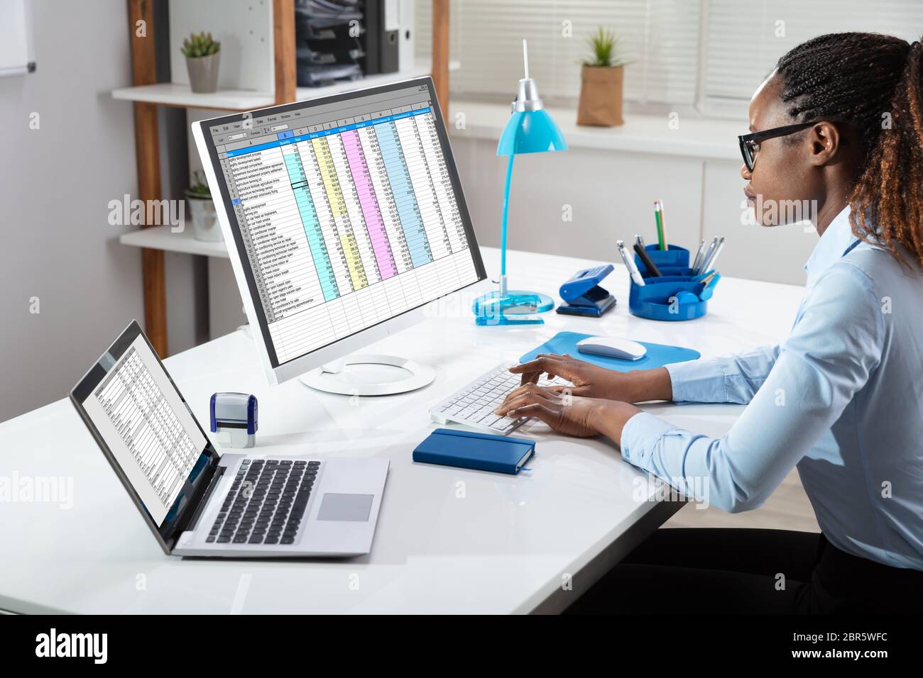 Side View Of Businesswoman's Hand Analyzing Data On Computer Over Desk Stock Photo