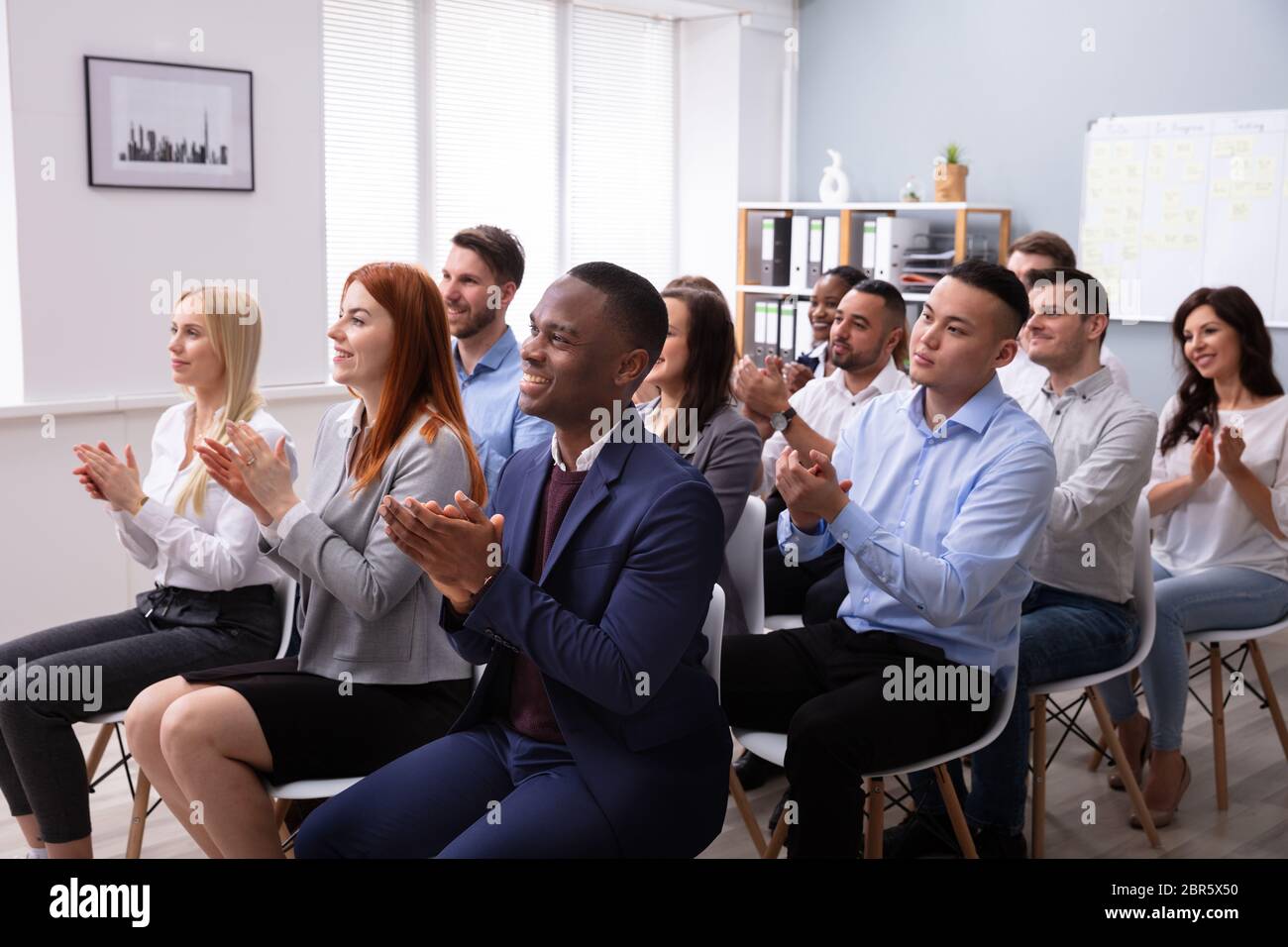 Audience Sitting On Chair In Row Applauding Speaker After Conference