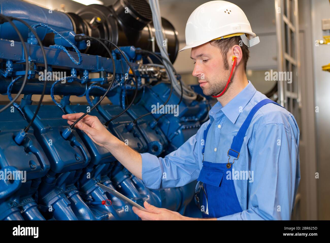 worker with helmet and clipboard working on big generator Stock Photo -  Alamy