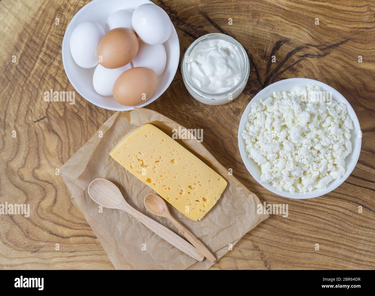 Rustic products on a textured wooden table cottage cheese, eggs, sour