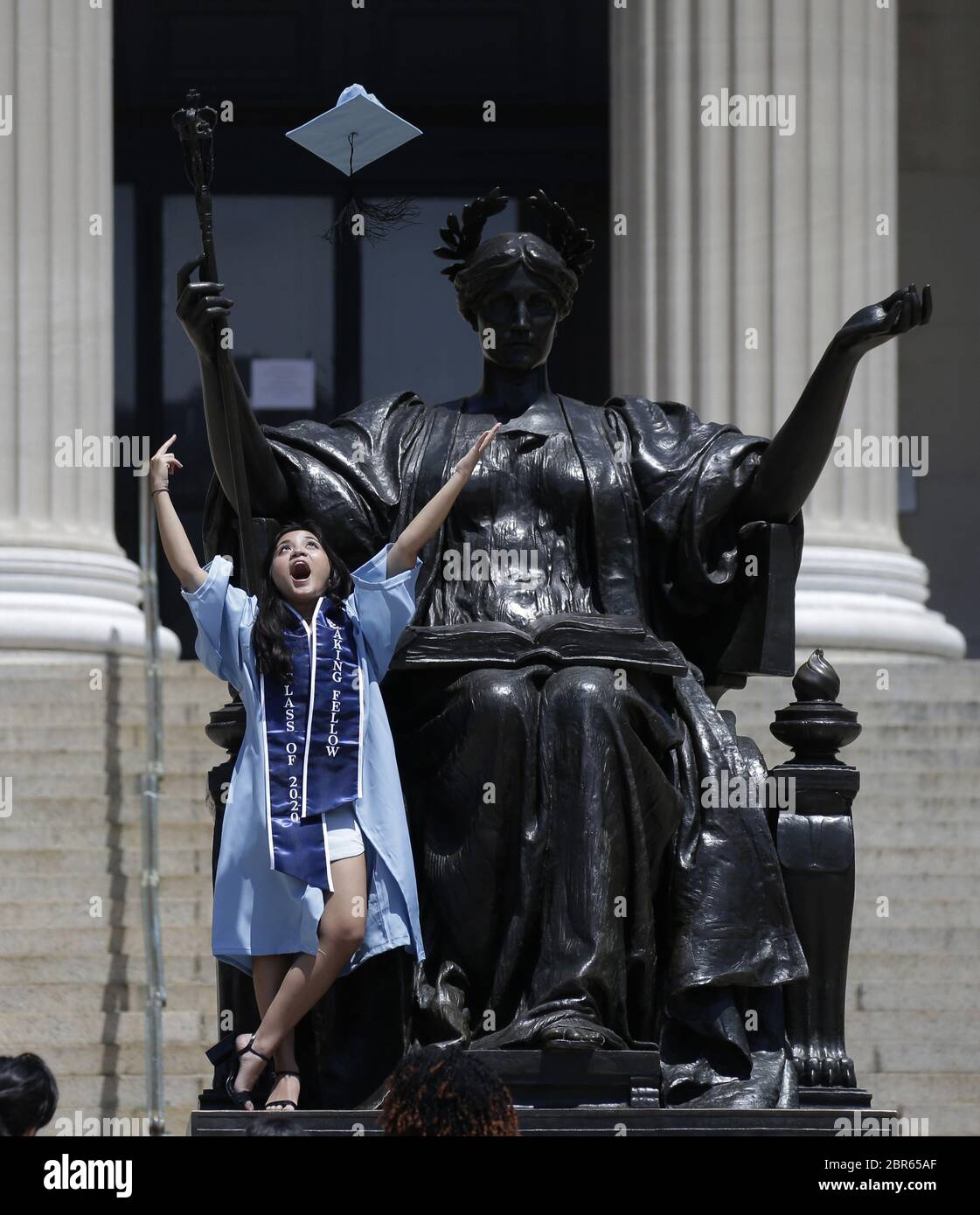New York, United States. 20th May, 2020. A graduate celebrates and throws  her cap in the air on the steps to the Library known as "Low Beach" after  Columbia University holds the