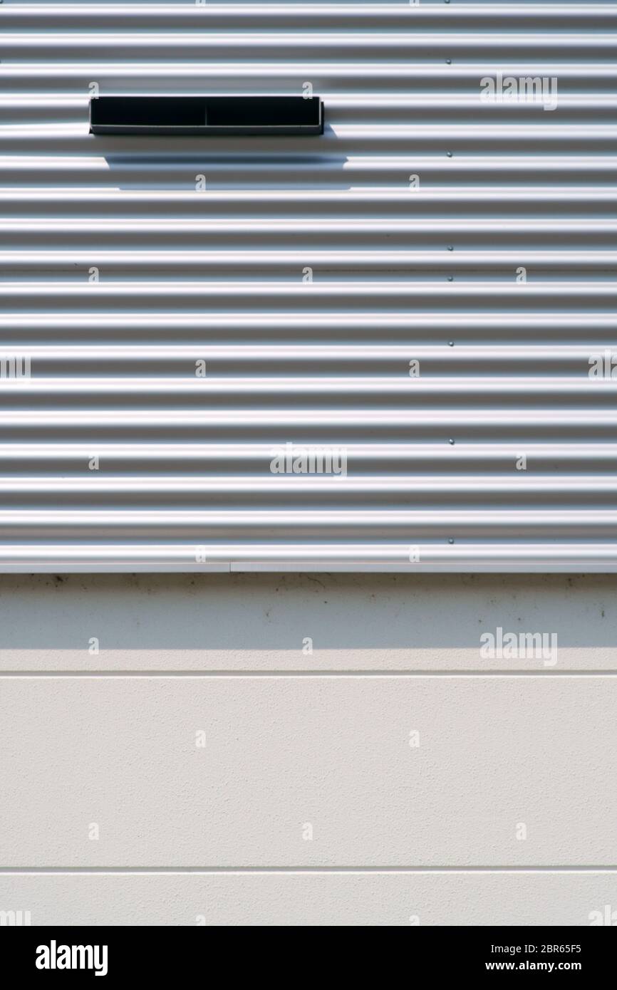 The detail of the surface of a round corrugated iron facade with ventilation slot. Stock Photo