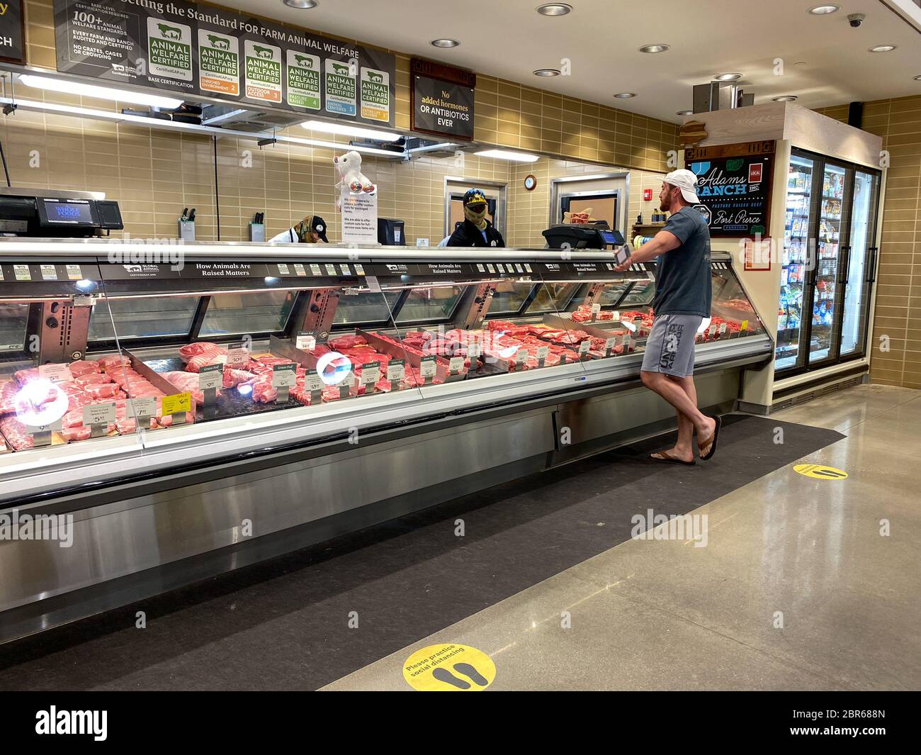 Orlando, FL/USA-5/3/20:  The meat counter at a Whole Foods Market  grocery store with a customer purchasing meat for meals. Stock Photo