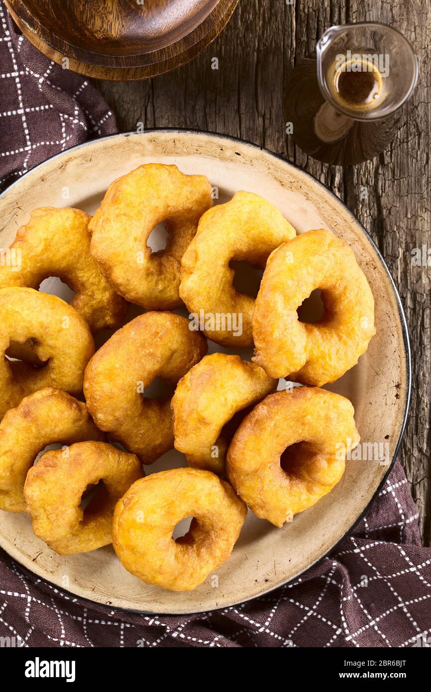 Traditional Chilean Picarones fried pastries made of pumpkin and flour yeast dough, served with sweet chancaca cane sugar sauce, photographed overhead Stock Photo