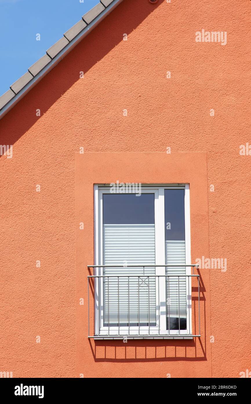 The roof edge and a window railing of a residential building cast shadows. Stock Photo