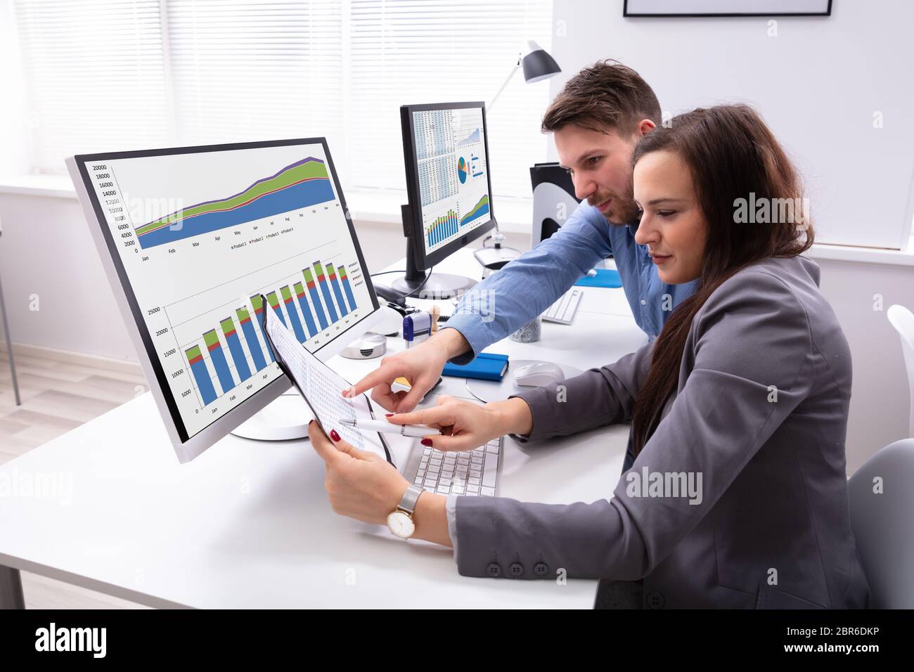 Two Smiling Businesspeople Discussing On Document While Working At Office Stock Photo