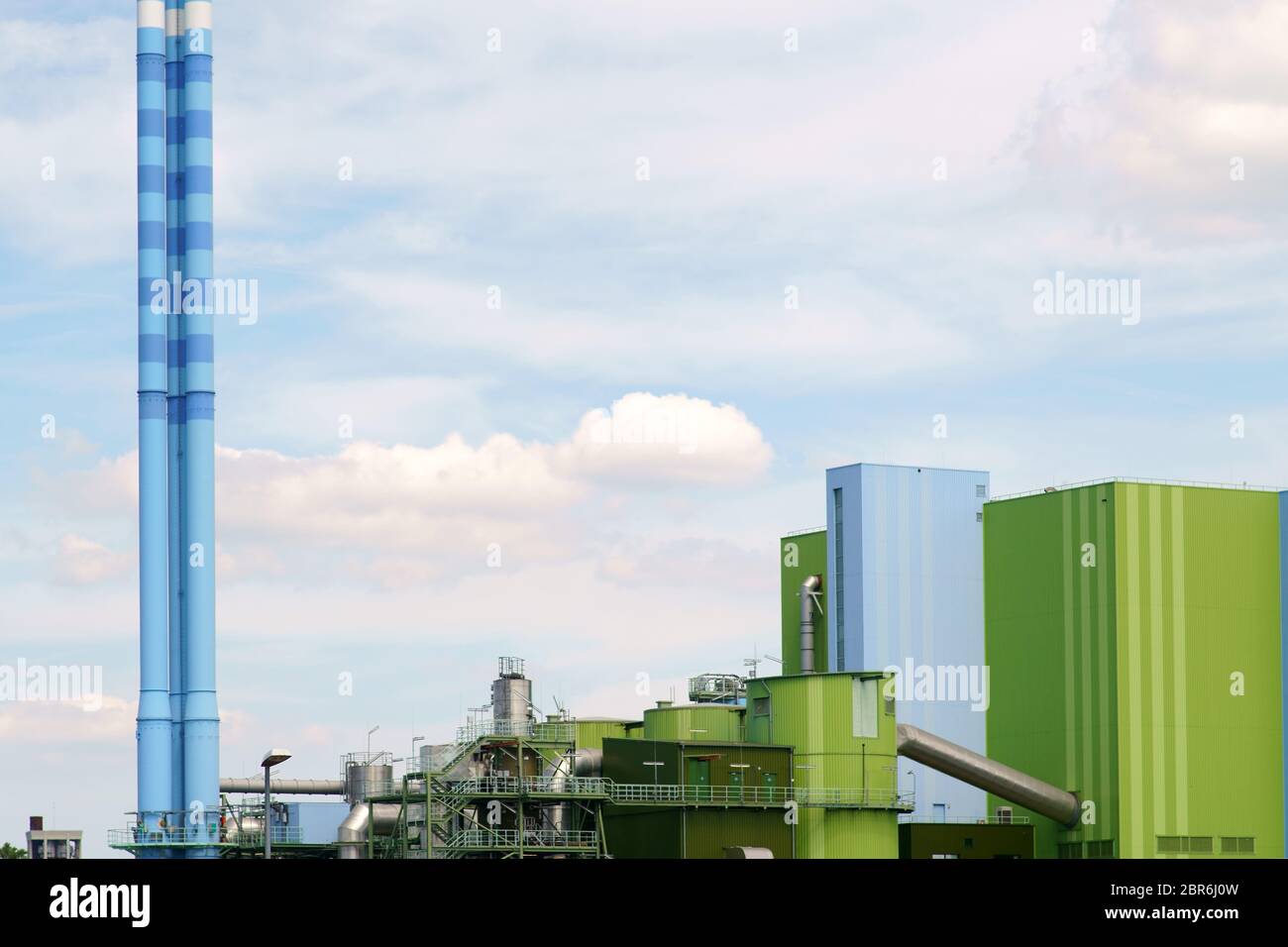 The colorfully painted chimney as well as the industrial buildings of a power plant. Stock Photo
