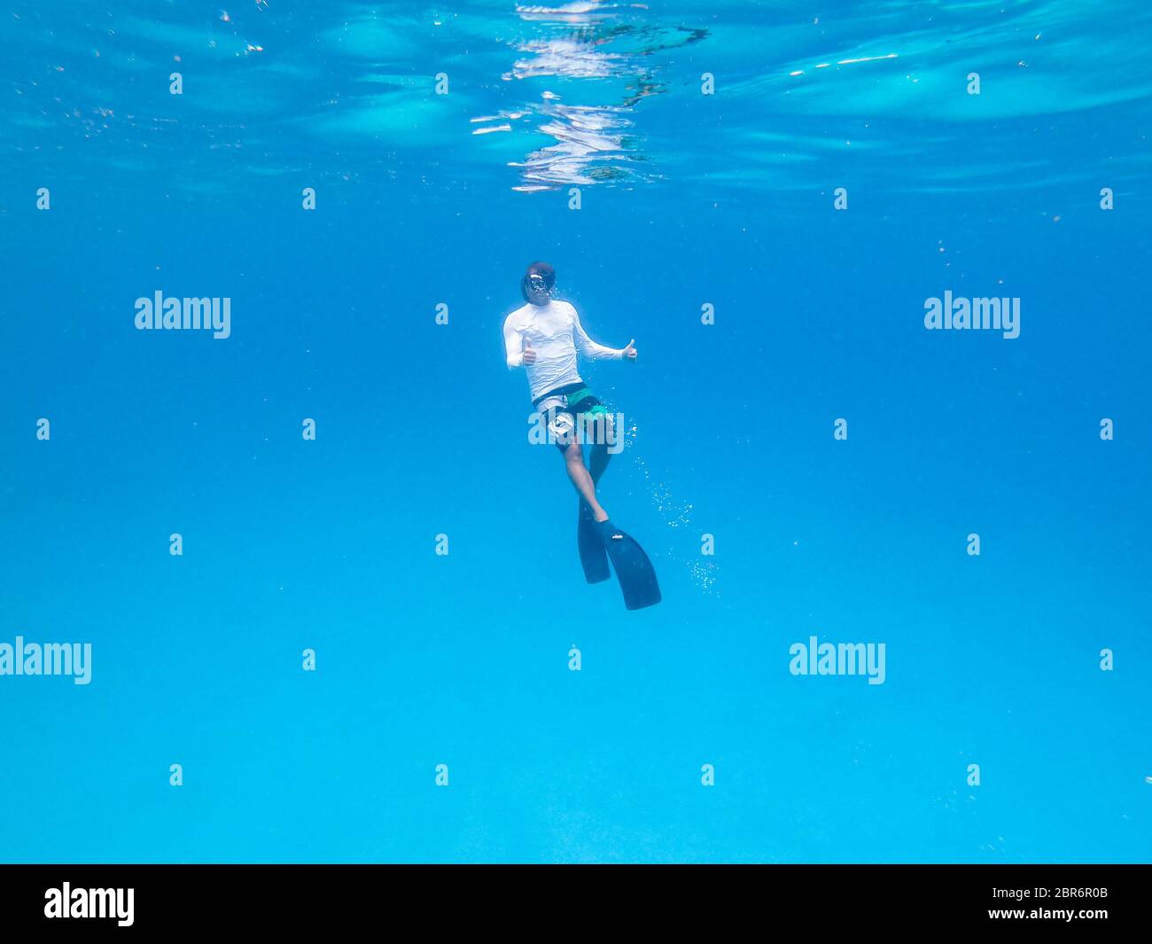 Underwater view of man free diving in blue ocean. Stock Photo