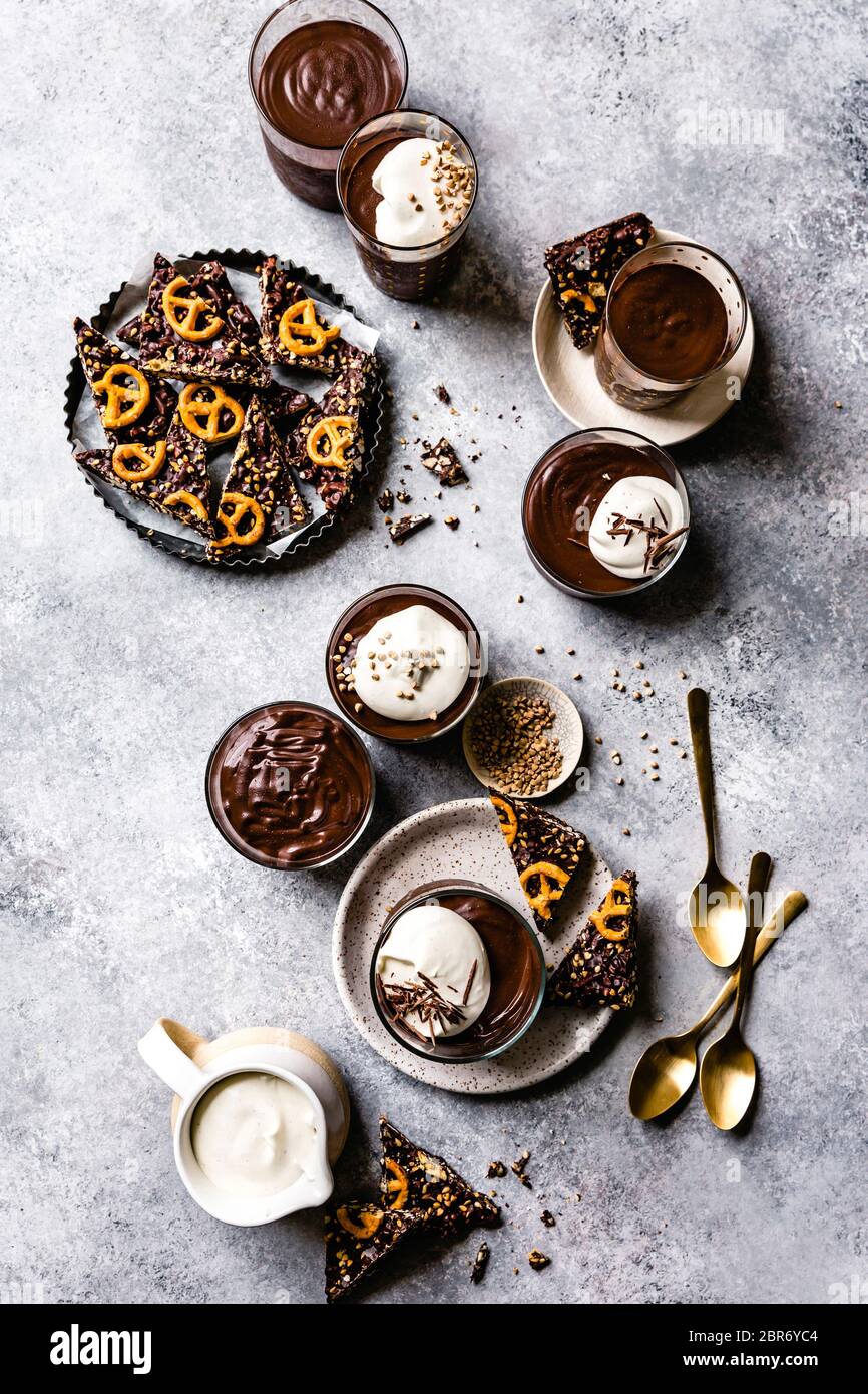 Individual chocolate puddings served with whipped coconut cream and a pretzel bark. Stock Photo