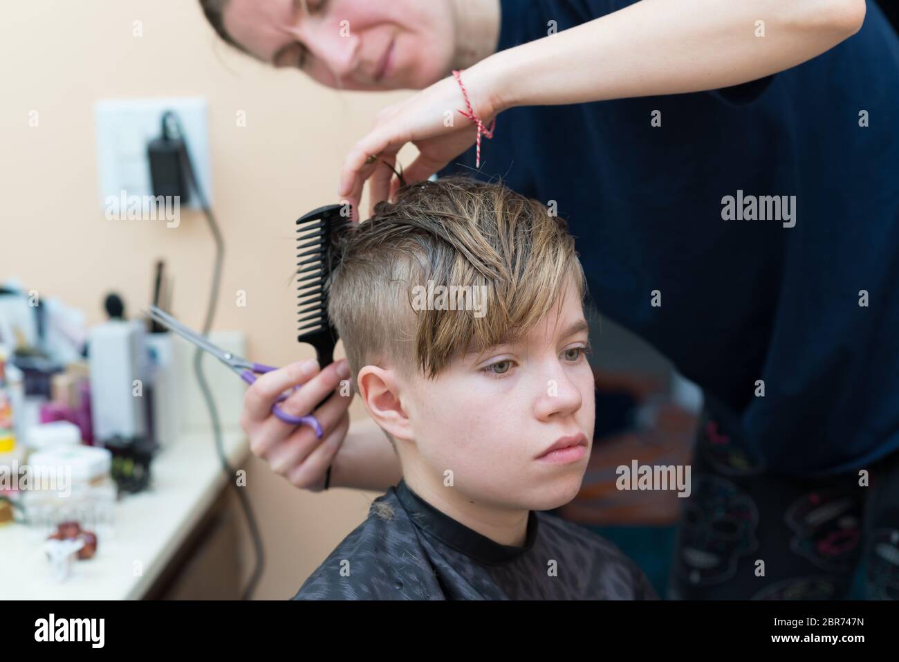 Mom cuts the hair of her son at home during quarantine amid COVID-19  coronavirus pandemic Stock Photo