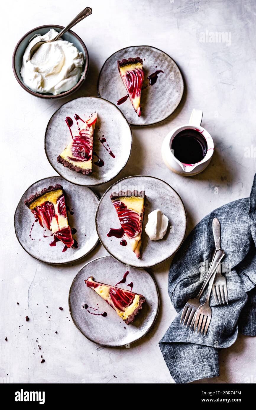 Servings of red wine poached pear custard tart with creme fraiche and
