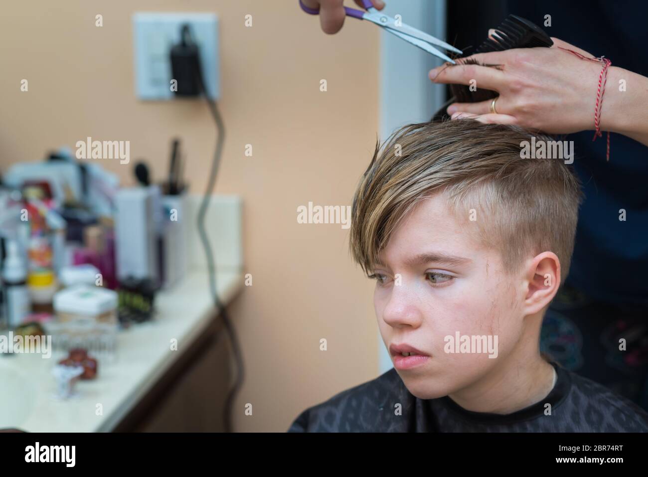 Mom cuts the hair of her son at home during quarantine amid COVID-19  coronavirus pandemic Stock Photo