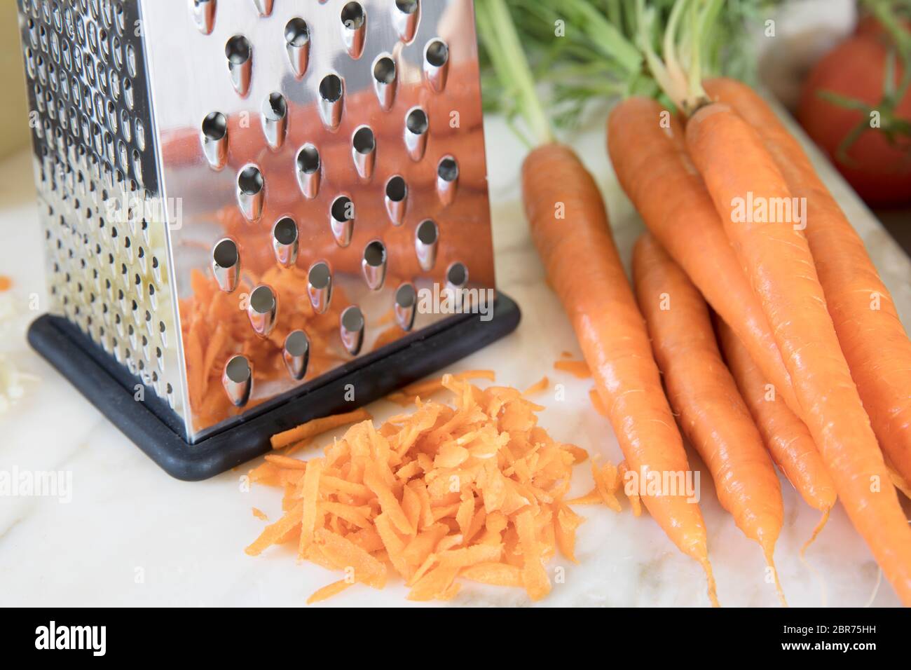 A large piece of carrots lies on a grater. Interrupted shredding