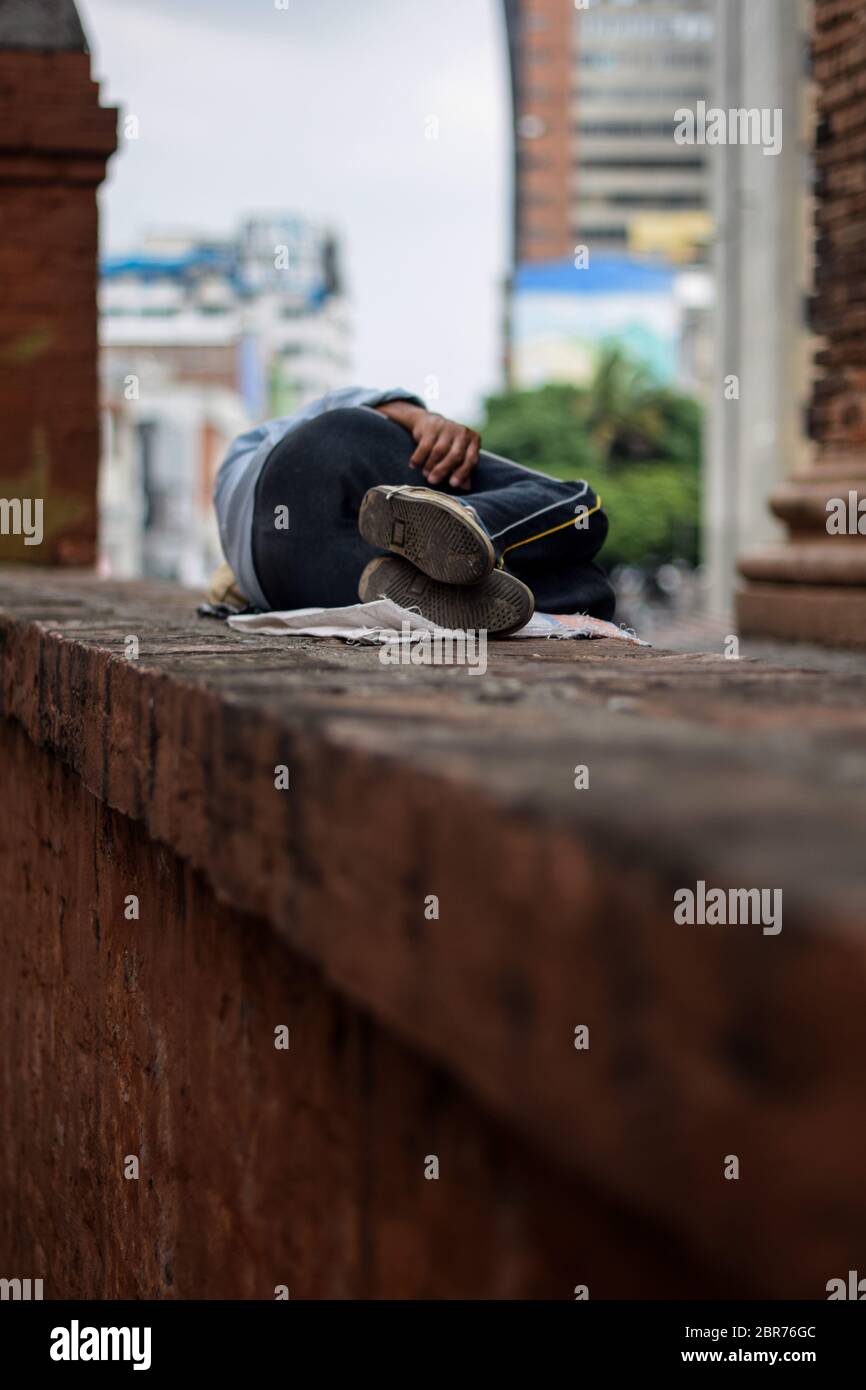 Homeless man sleeps on church wall during Coronavirus outbreak in Colombia Stock Photo