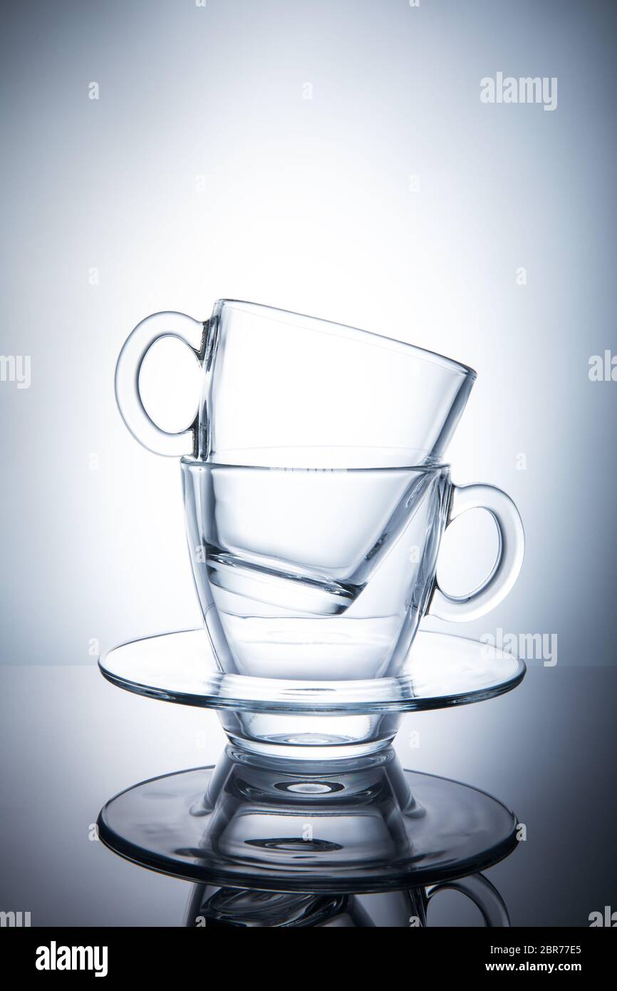 Two isolated transparent tea cups with saucers. Stock Photo