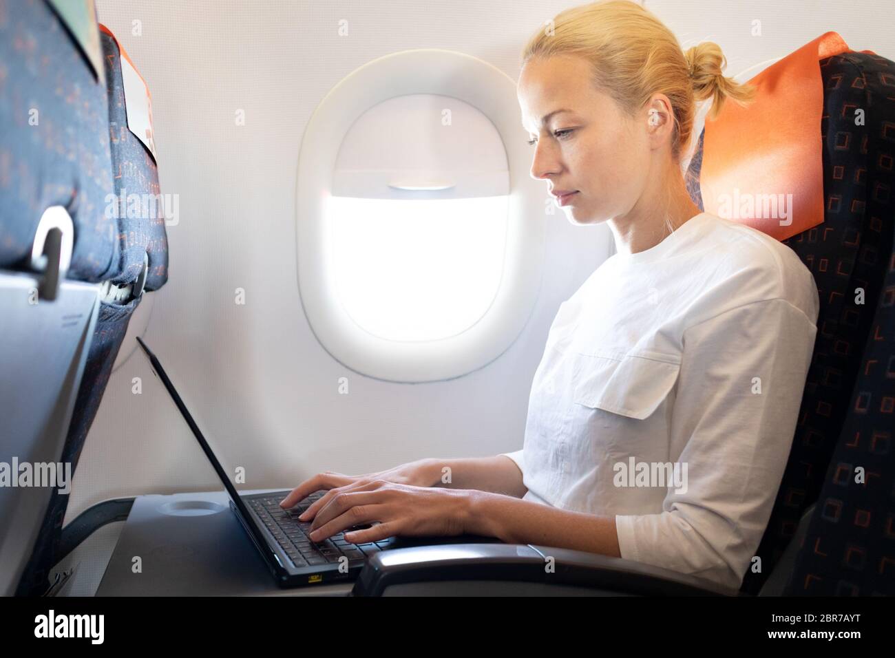 Attractive caucasian female passenger working at modern laptop computer ...