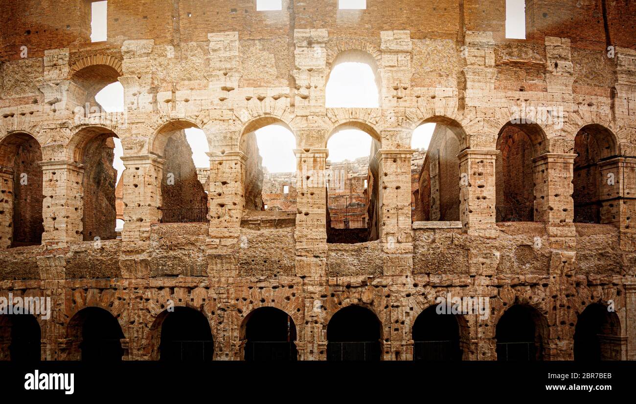 the Colosseum of Rome during sunset with sun rays filtering through the ...