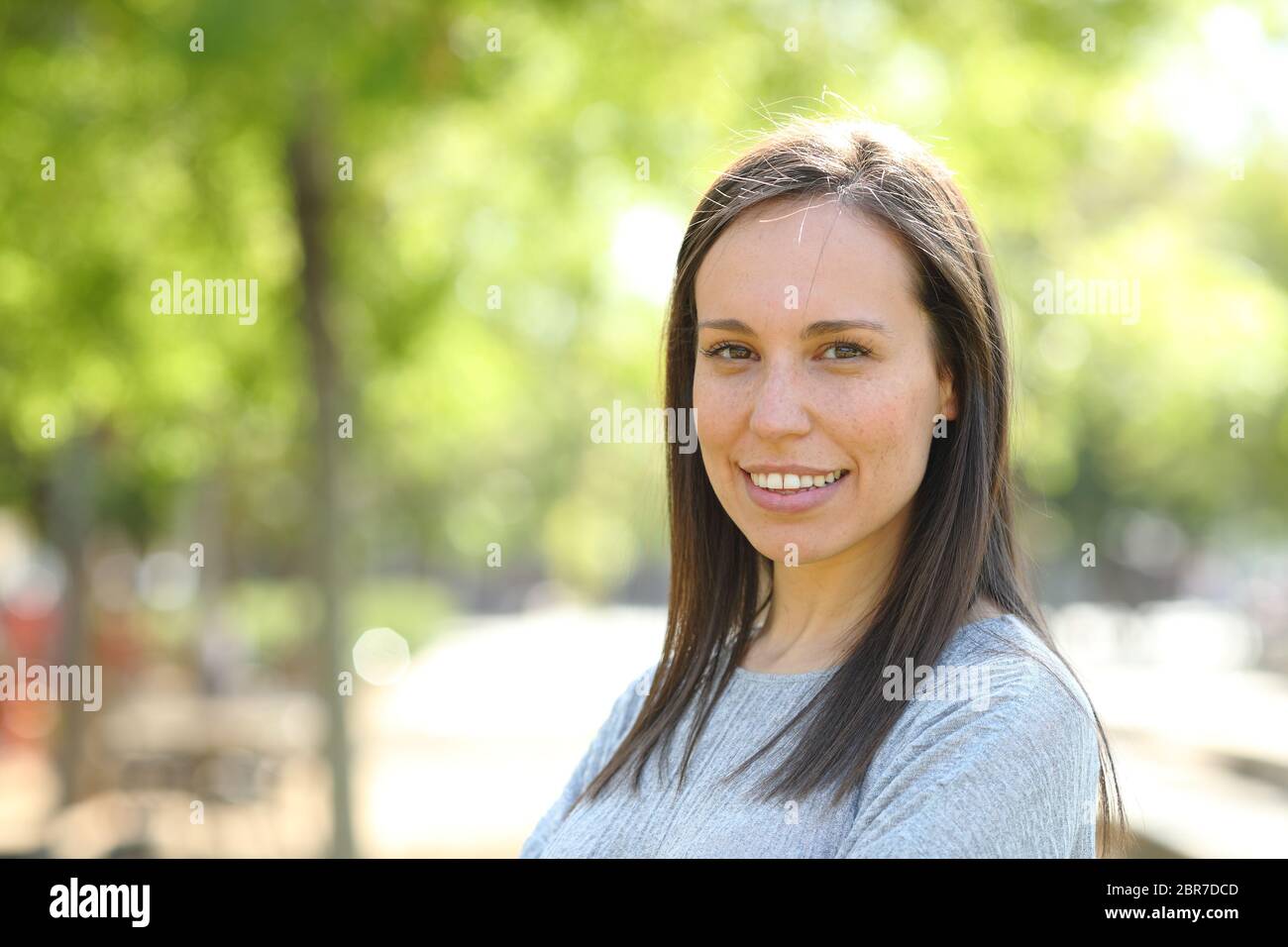Portrait of a happy woman looking at camera standing outdoors in a ...