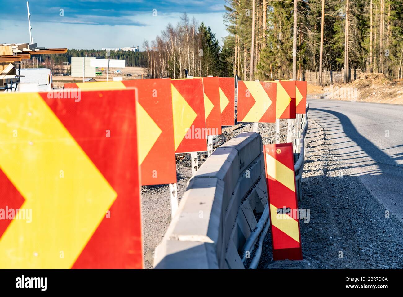 Close up photo at row of warning direction drive signs, temporarily placed at corner of road under construction to avoid collision with concrete fence Stock Photo