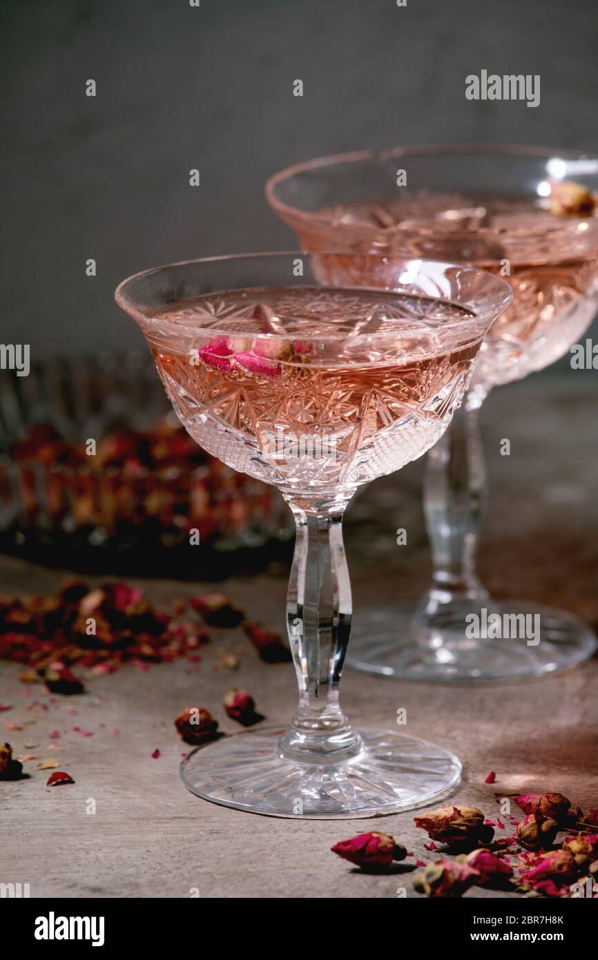 Crystal vintage glasses of pink rose champagne, cider or lemonade with dry  rose buds. Grey texture background Stock Photo - Alamy