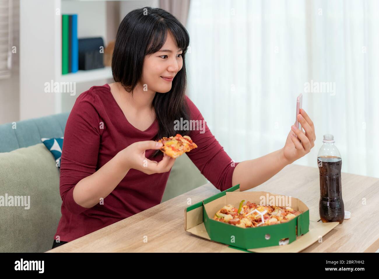 Asian woman virtual happy hour meeting dinner and eating pizza food online together with her boyfriend in video conference with digital tablet for a o Stock Photo