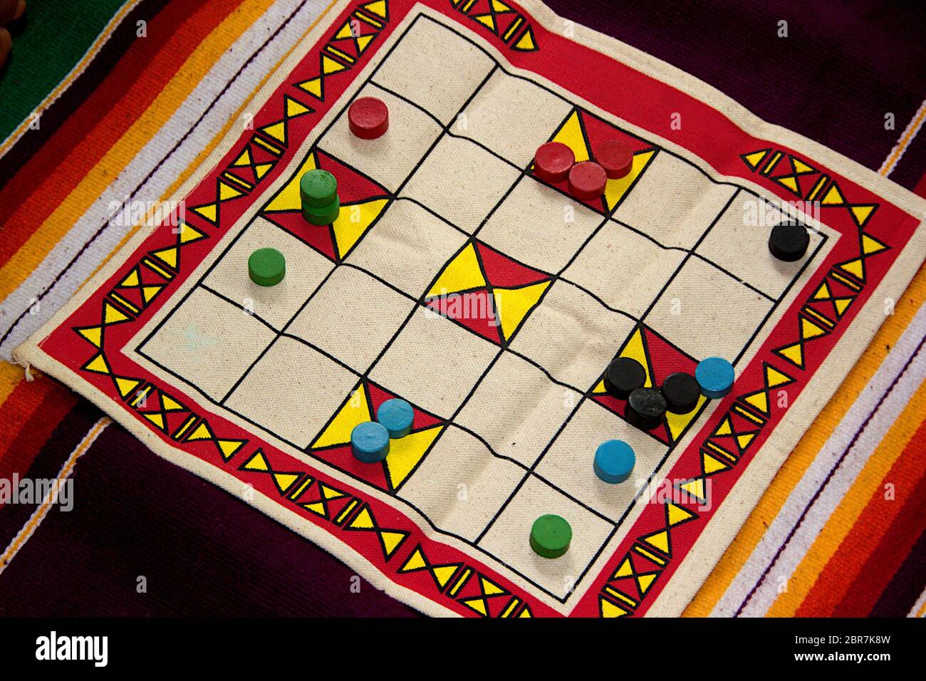 Popular board game colorfully printed on woven cloth with tablet shaped color coins for each player Stock Photo