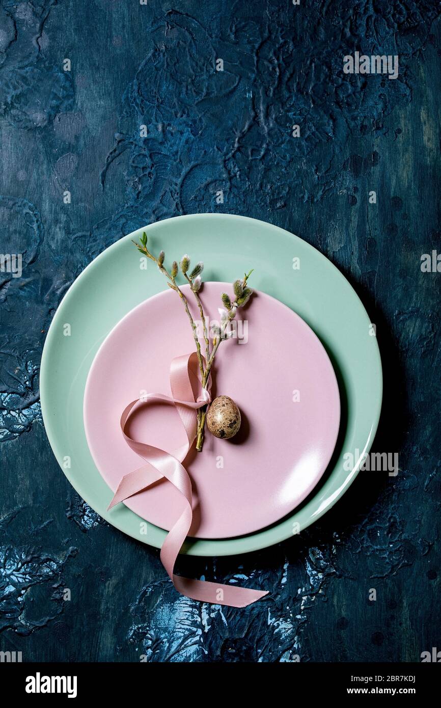 Easter table setting with empty plates with blossom willow branches and golden quail egg. Classic blue texture background. Flat lay, space Stock Photo