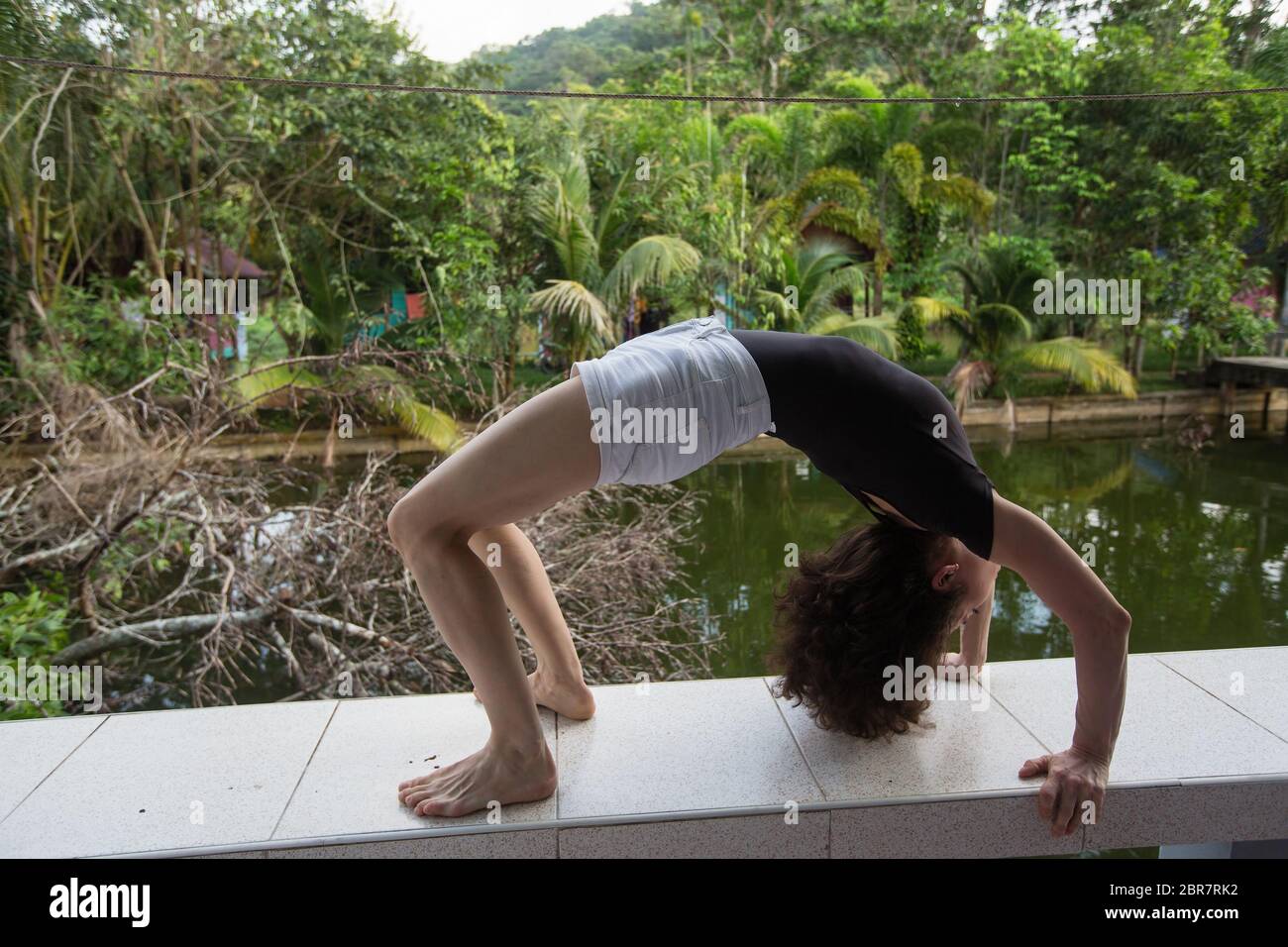 Asian Girl In The Bridge Pose On The Terrace Of The Bungalow Stock Photo Alamy