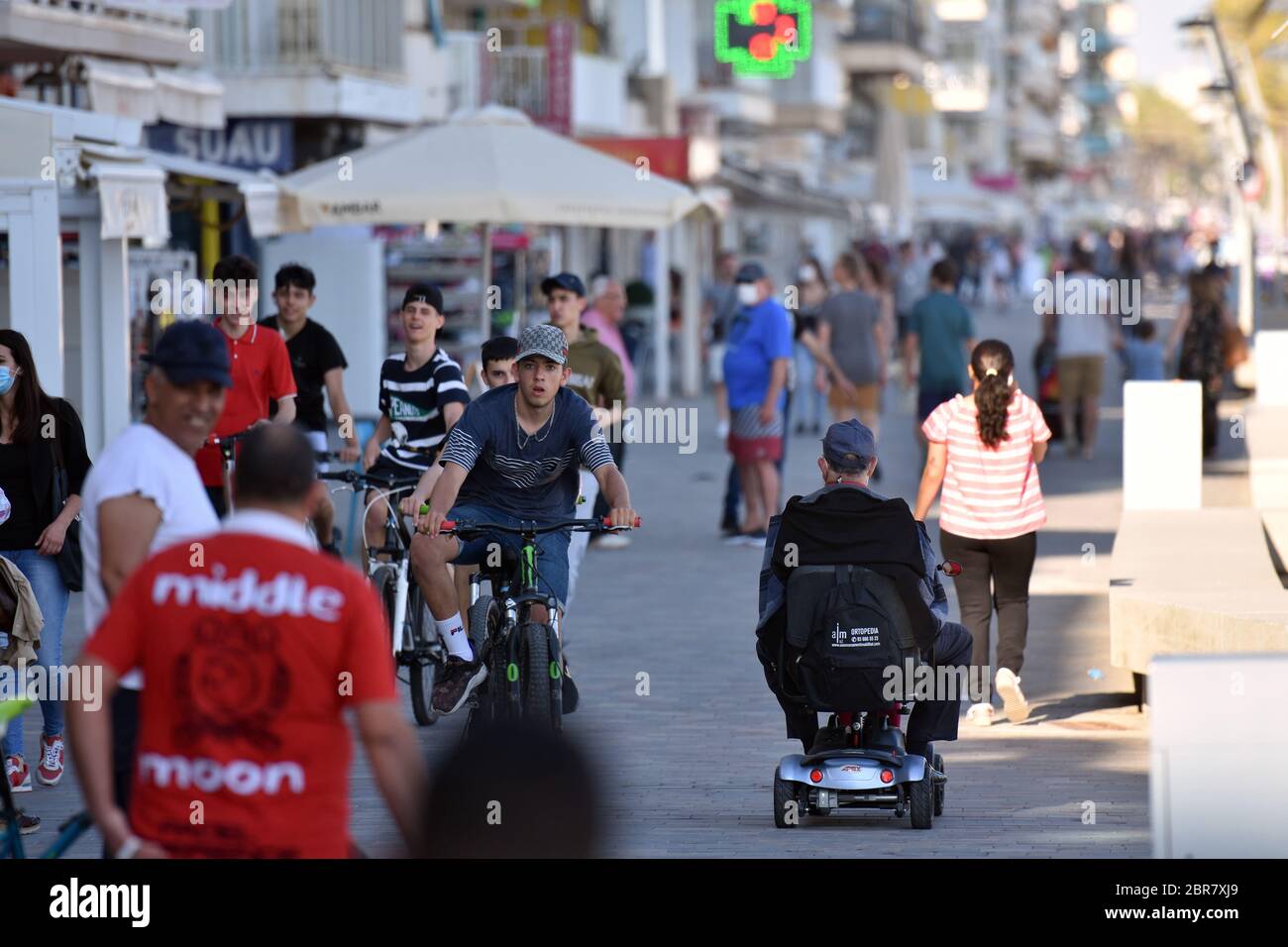 People ride and walk along Paseo Maritimo street during the end of the confinement of Phase One.Calafell is in Phase One of the end of confinement but with strict measures where you can be on the terraces of the restaurants with the security measures of 2 meters between the tables, walk on the beach but not be sitting stretched out on the sand or bathing. The local police carry out street patrols to control compliance with the regulations. Stock Photo