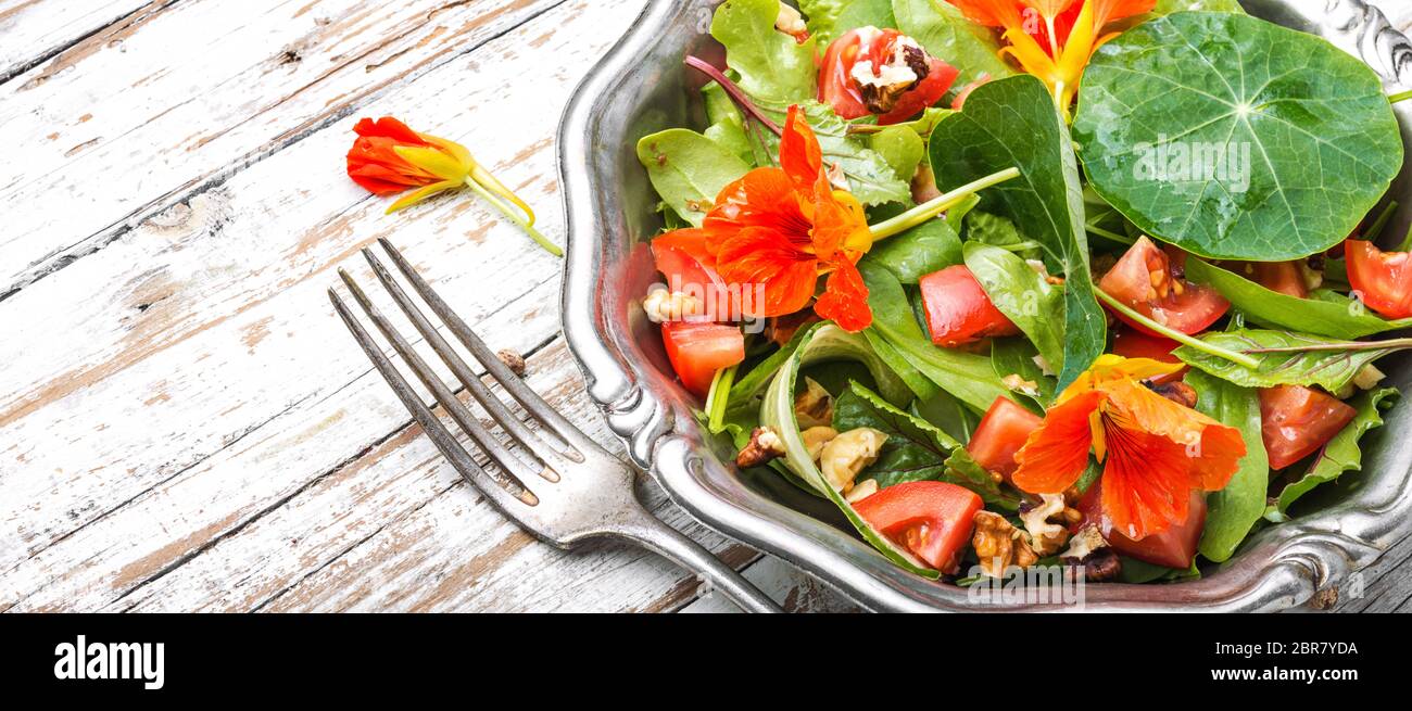 Healthy salad with flowers, nasturtium leaves, tomatoes and nuts. Summer food.Indian salad.Capuchin Stock Photo