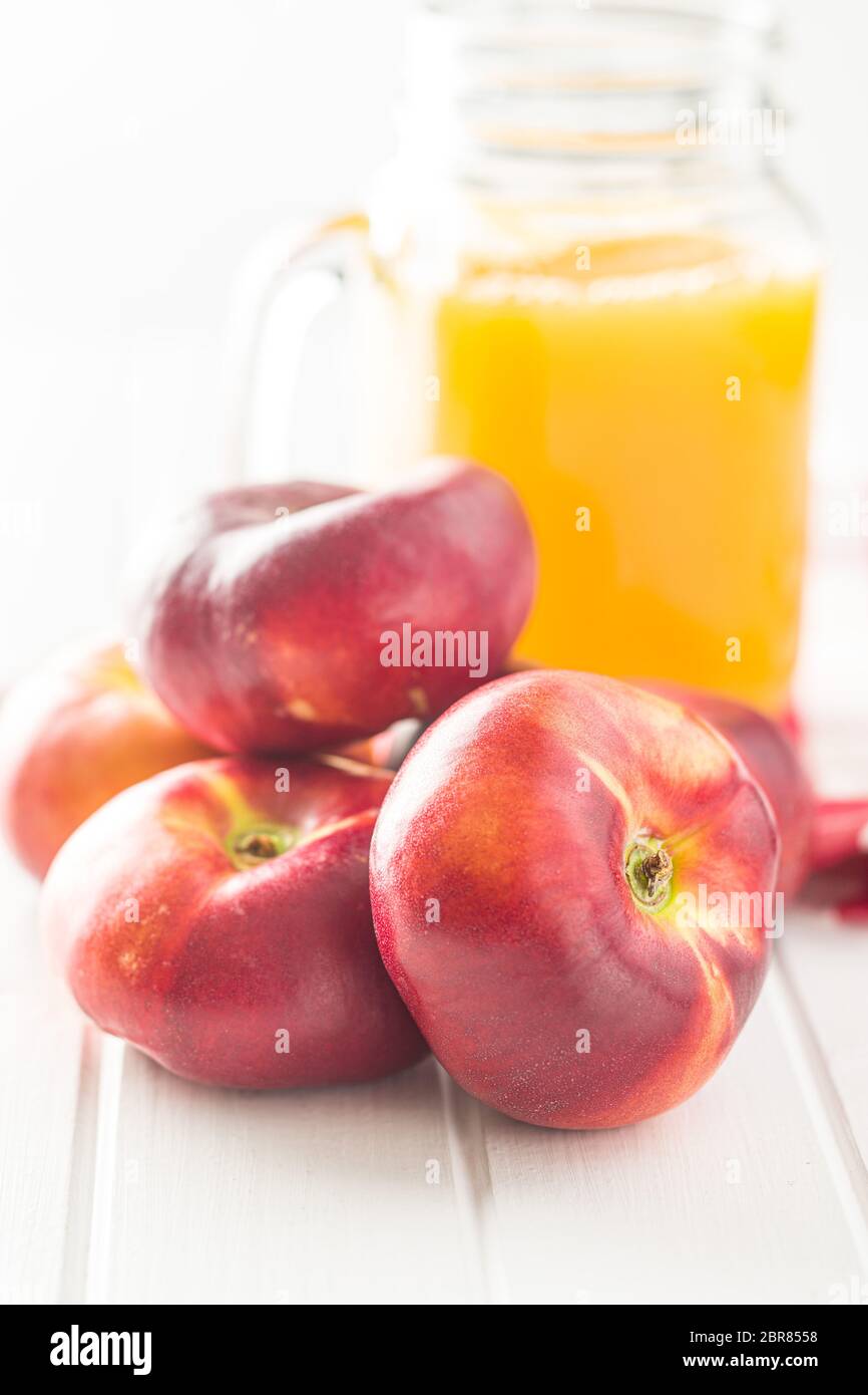 Ripe flat nectarines and juice glass on white table Stock Photo Alamy