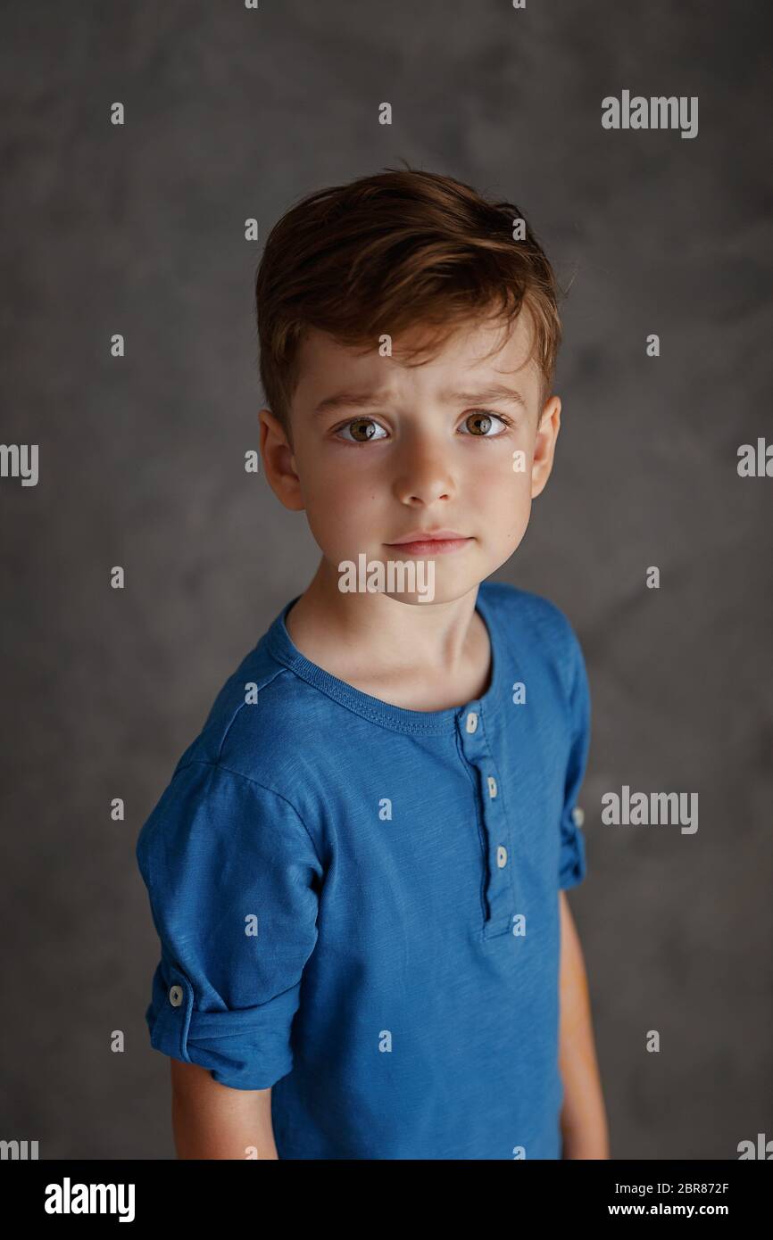 5 year old boy blue shirt and yellow pants studio portrait on gray