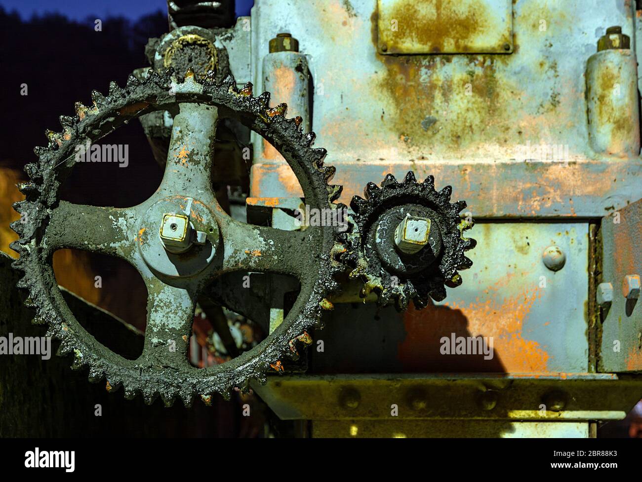Vintage oily and rusty illuminated cogwheel at night Stock Photo