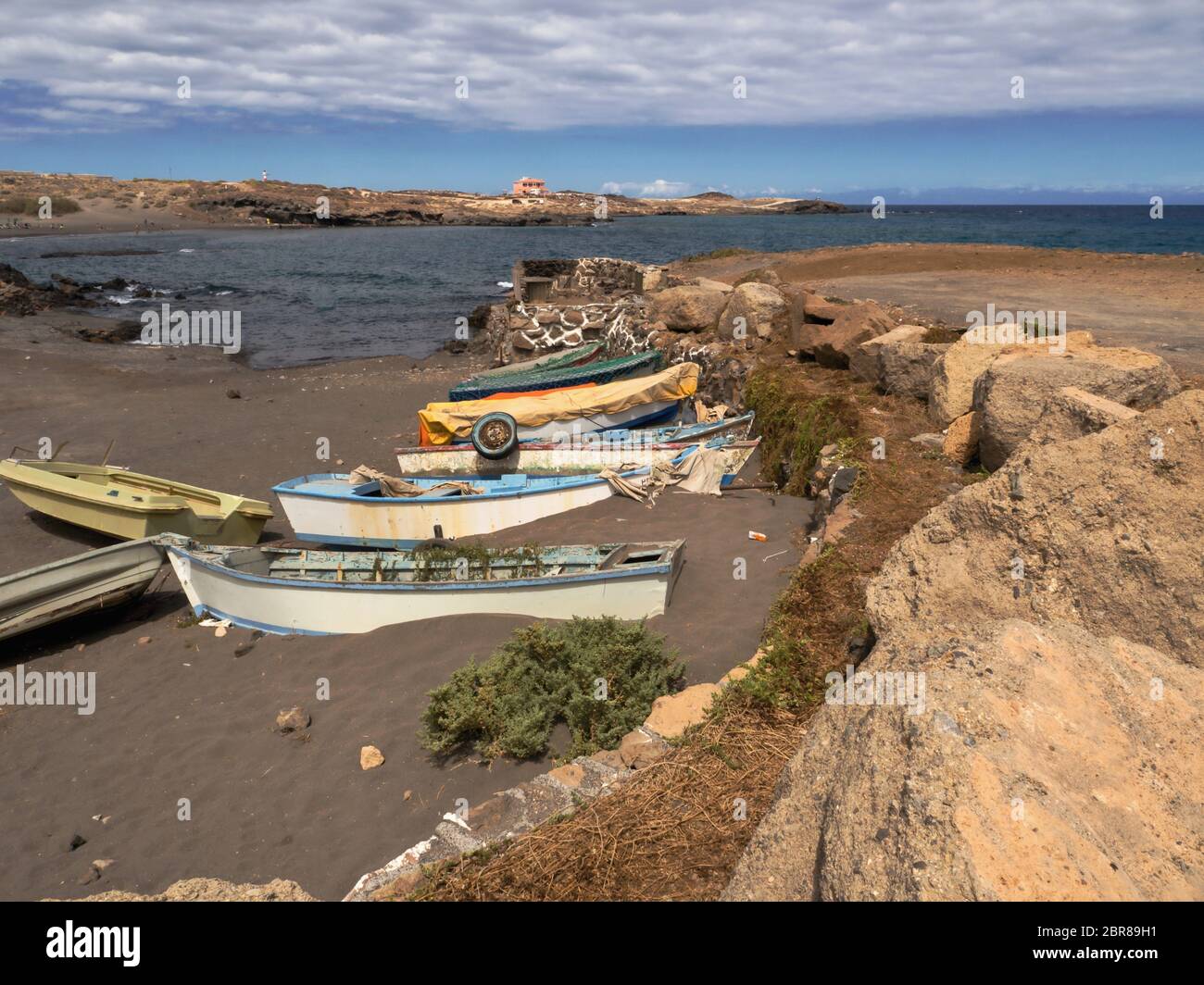 small, old wooden fishing boats, colorfully painted, are located on the black Volcanicsand-beach right in front of the Atlantic Ocean in the village A Stock Photo