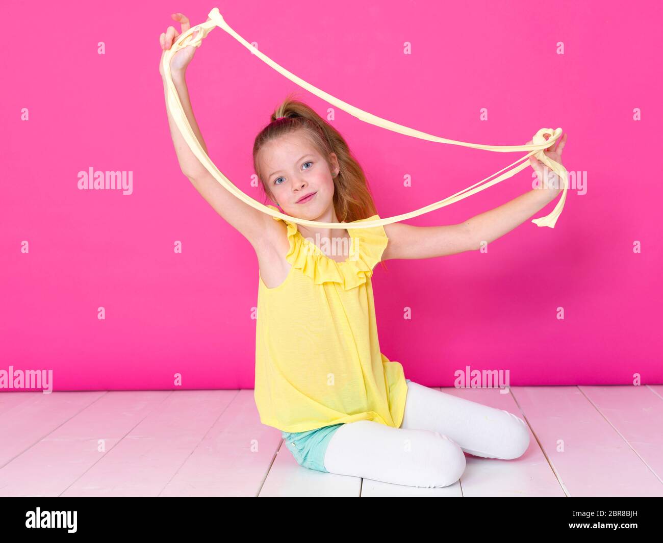 beautiful 10 year old girl is playing with yellow slime in front of