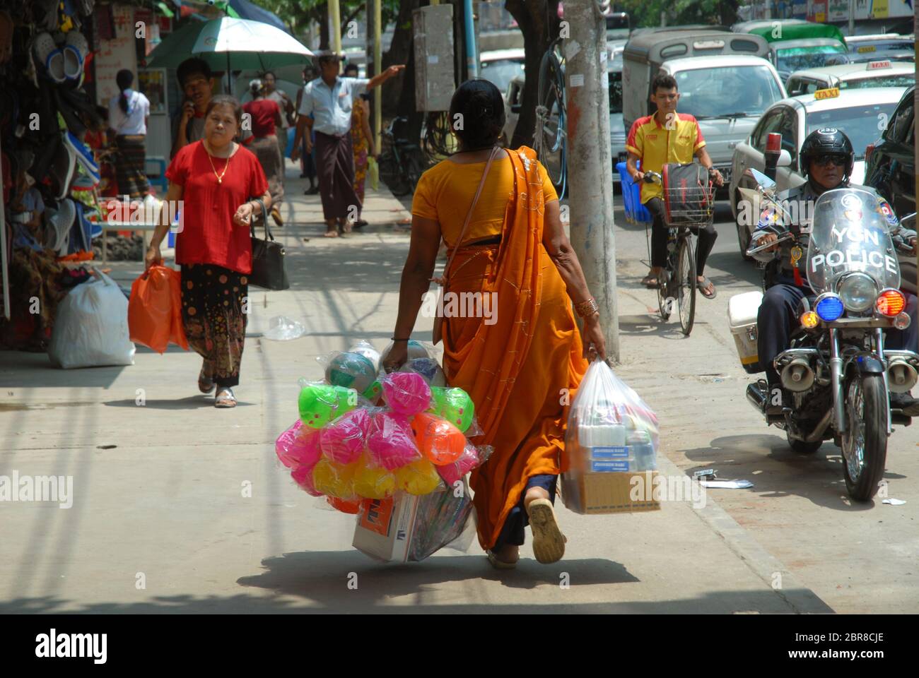 Lady carrying large bags of colourful plastic toys, Yangon, Myanmar