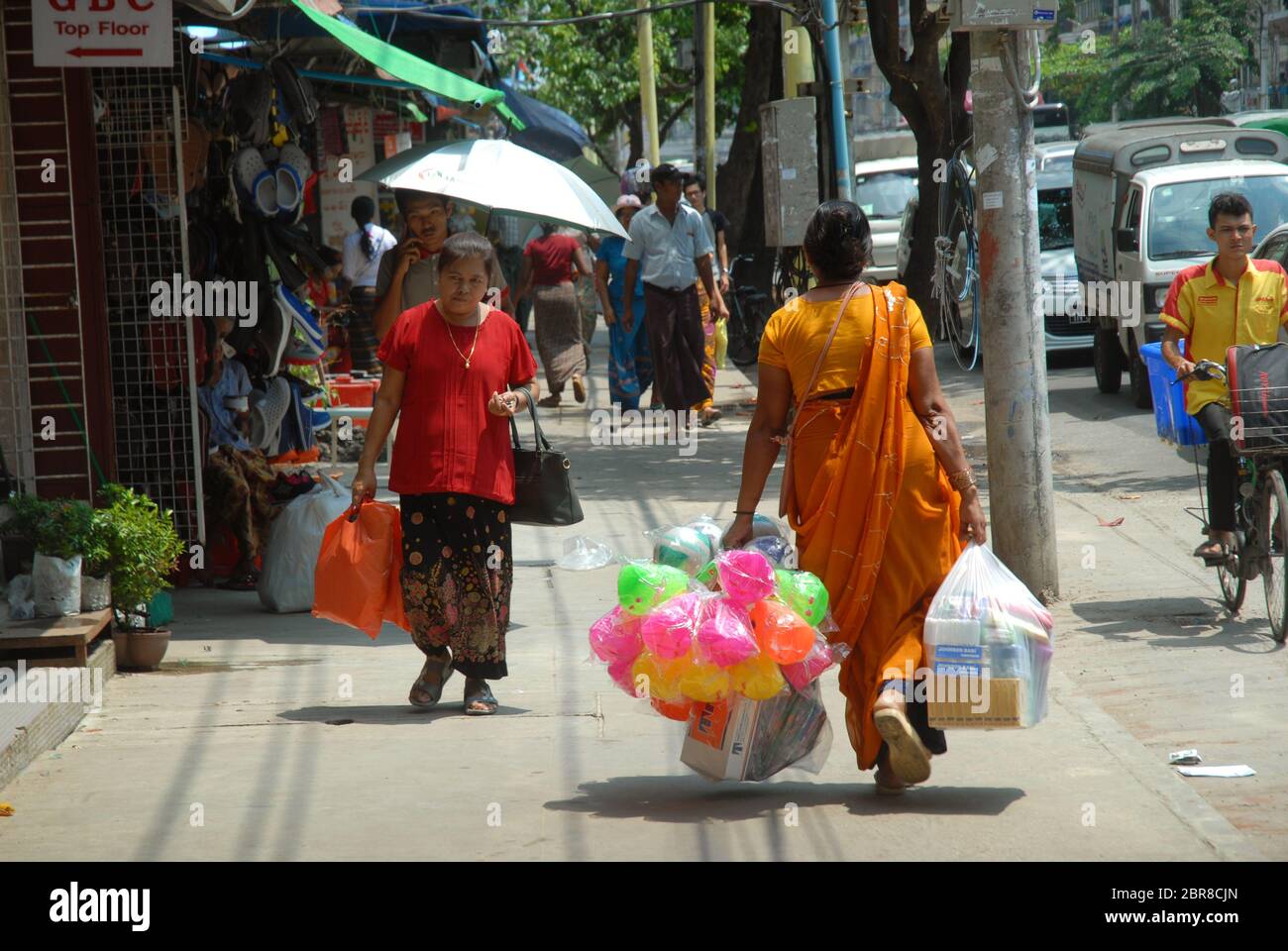 Lady carrying large bags of colourful plastic toys, Yangon, Myanmar
