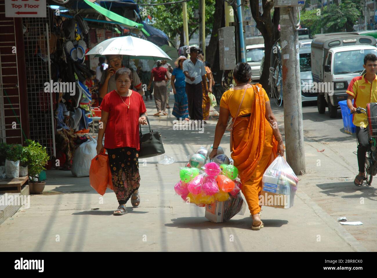 Lady carrying large bags of colourful plastic toys, Yangon, Myanmar