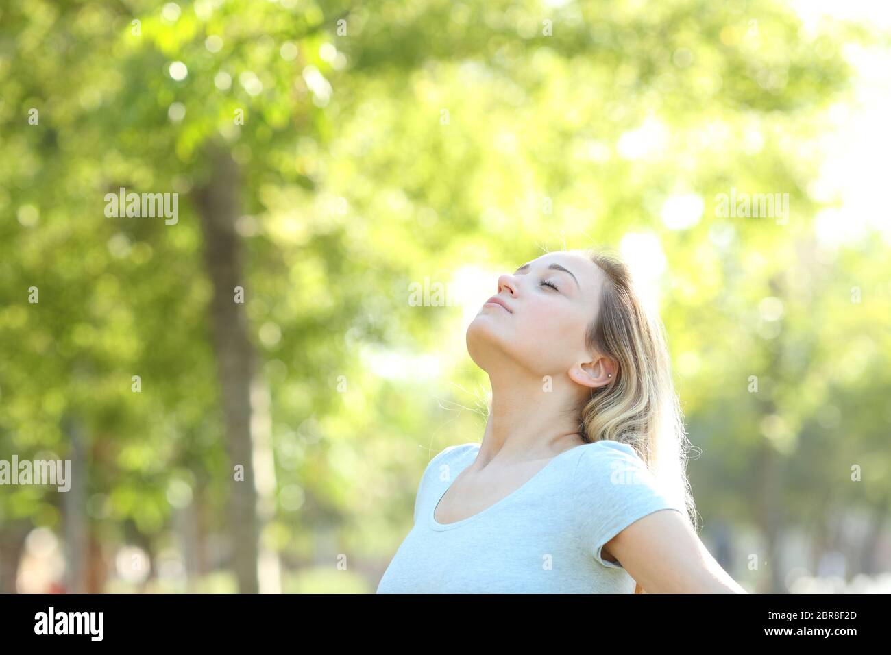 Relaxed teenage girl breathing deeply fresh air in a park or forest ...