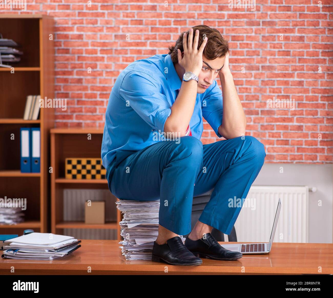The young employee with excessive work sitting at the office Stock ...