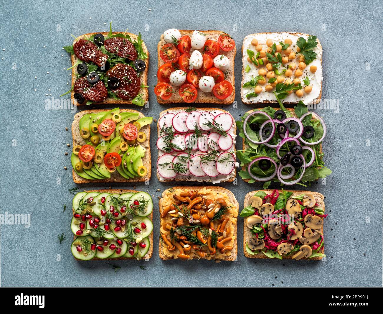 Assortment vegan sandwiches on gray stone background. Set different vegetarian smorrebrod. Top view or flat lay. Stock Photo