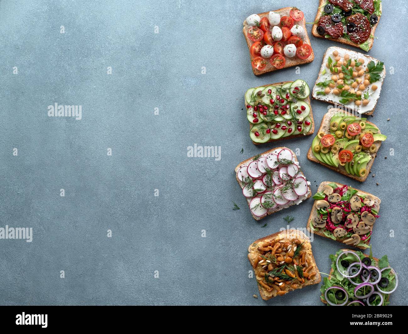 Assortment vegan sandwiches on gray stone background. Set different vegetarian smorrebrod. Top view or flat lay. Copy space for text. Stock Photo