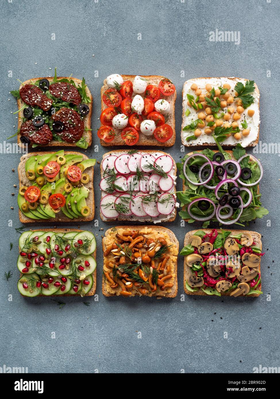 Assortment vegan sandwiches on gray stone background. Set different vegetarian smorrebrod. Top view or flat lay. Vertical Stock Photo