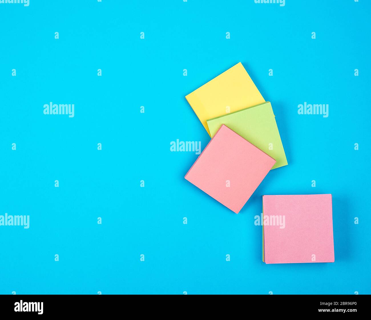 multicolored empty paper square stickers on blue background, copy space Stock Photo