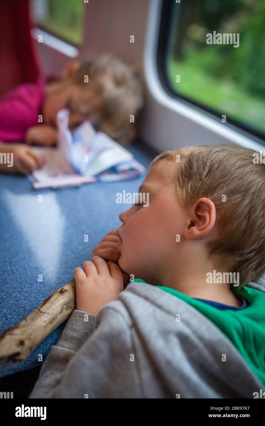 Little Caucasian boy and girl asleep inside the train carriage on their trip back home Stock Photo