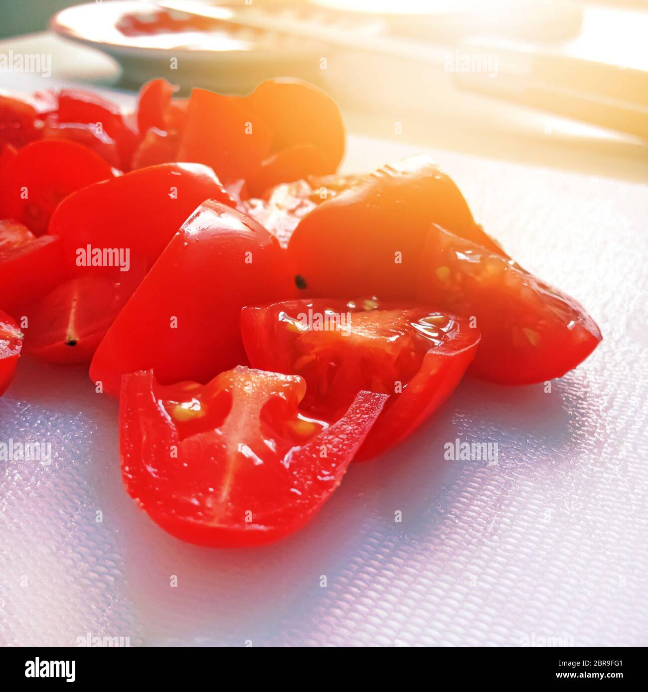 close-up view of sliced cherry tomatoes on a white cutting board ...